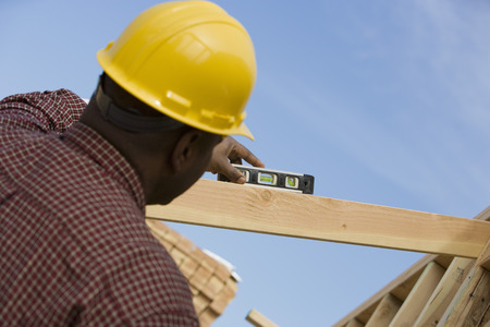 Construction worker using spirit level on building