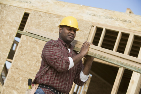 Construction worker carrying wooden plankの写真素材