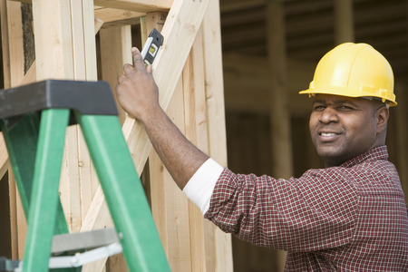 Construction worker using spirit level on building