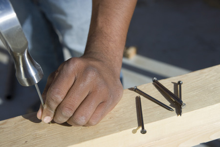 Man hammering nails to wooden plank