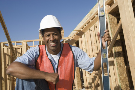 Construction worker holding spirit level on construction site
