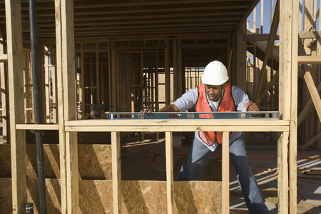 Construction worker using spirit level on construction site