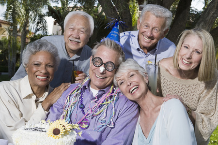 Senior people celebrating birthday in garden, smilingの写真素材