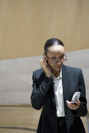 Business woman using mobile phone, indoorsの写真素材