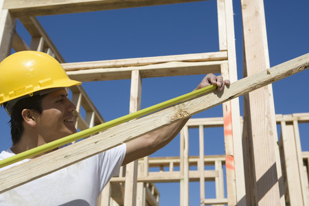 Construction worker measuring plank