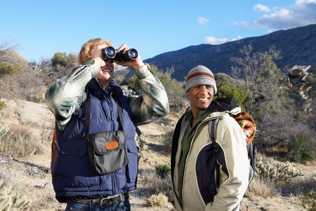Two Young Men Using Binoculars While Hikingの写真素材
