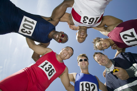 Male sprinters in huddle, view from belowの写真素材