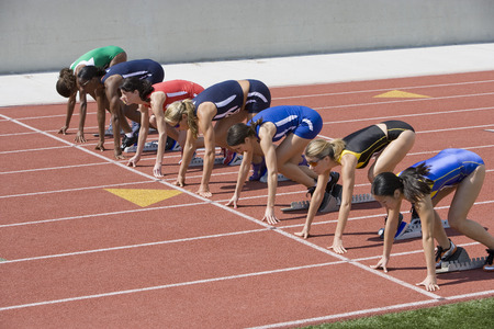Female athletes in starting blocks, ready to runの写真素材