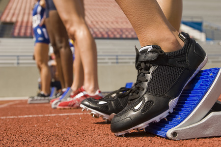 Group of female track athletes on starting blocks, close-up viewの写真素材
