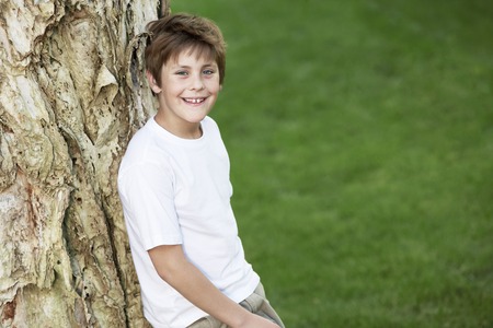 Smiling Boy Leaning Against Treeの写真素材