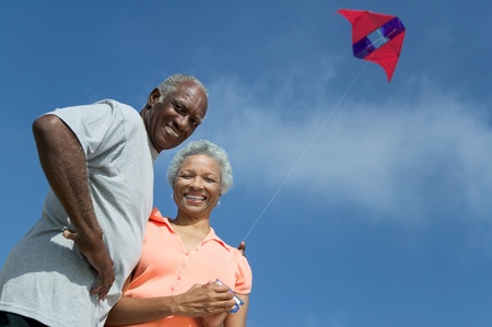 Senior couple flying kite outdoors (low angle view) (portrait)の写真素材