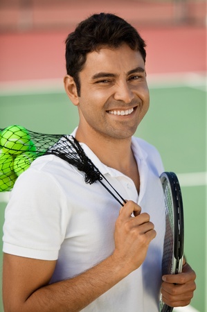 Man with on tennis court with tennis balls and racket portraitの写真素材