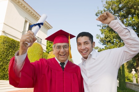 Senior Graduate hoisting diploma with son outside portraitの写真素材