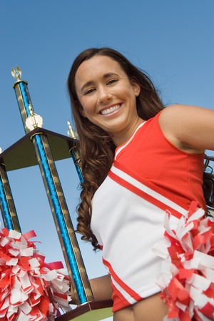 Smiling Cheerleader holding trophy (portrait) (low angle view)の写真素材