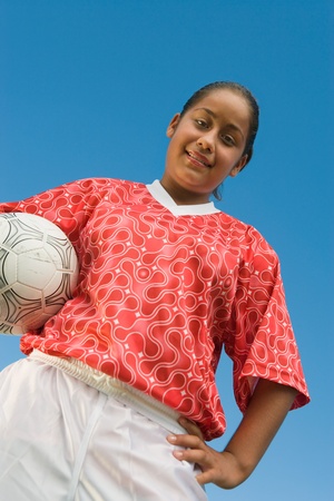 Girl (13-17) in soccer kit holding ball portrait low angle viewの写真素材
