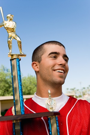 Baseball player holding trophy on field