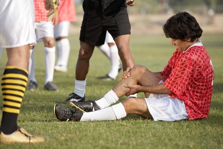 Injured soccer player sitting on pitch portraitの写真素材