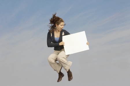 Woman holding blank sign mid-air outdoorsの写真素材