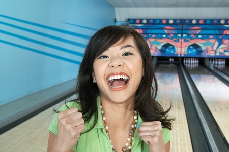 Young woman at bowling alley celebrating portraitの写真素材