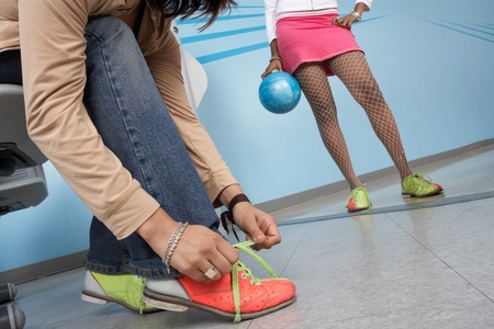 Young woman tying bowling shoes low sectionの写真素材