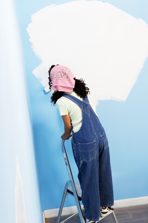 Woman standing on stepladder painting interior wall back view elevated viewの写真素材