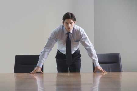 Businessman standing and leaning over conference room tableの写真素材