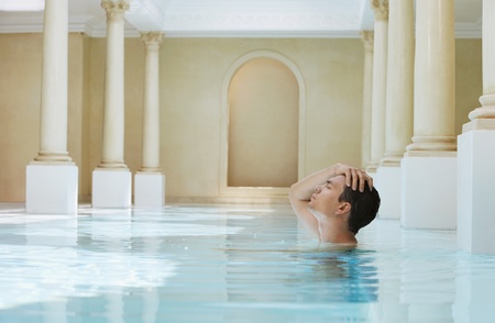 Young man with hand on head in swimming pool side view