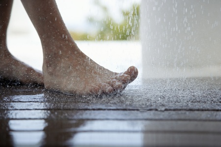 Woman standing under outdoor shower close up of feet low section 