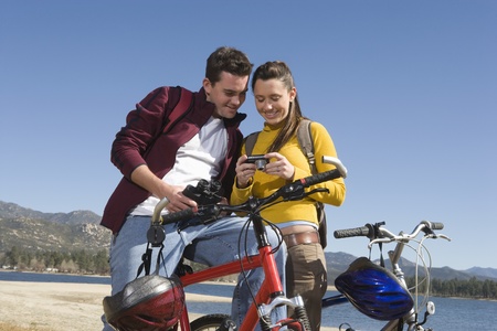 Young couple stand with mountain bike looking at screen of cameraの写真素材