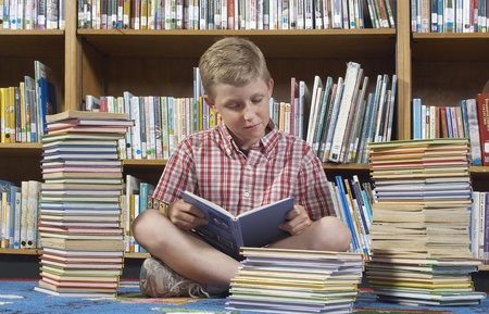 Boy sitting on the floor and reading book in library