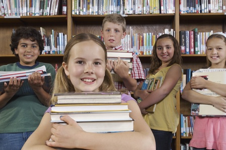 School children holding books in library portraitの写真素材