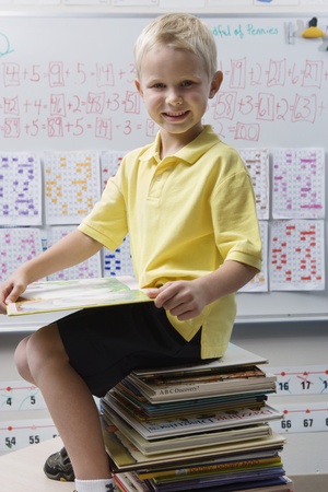 Schoolboy Sitting on a Stack of Booksの写真素材