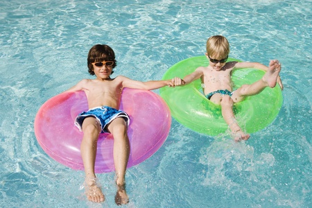 Boys on Float Tubes in Swimming Poolの写真素材