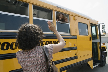 Mother Waving to Teenage Daughter on School Busの写真素材