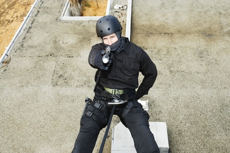 SWAT Team Officer Rappelling and Aiming Gunの写真素材