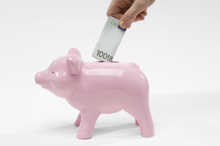 Hand Putting Money in Piggy Bankの写真素材
