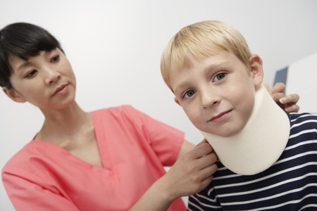 Nurse assisting boy wearing neck brace in hospitalの写真素材