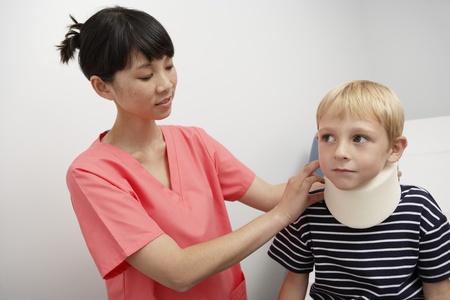Nurse assisting boy wearing neck brace in hospitalの写真素材