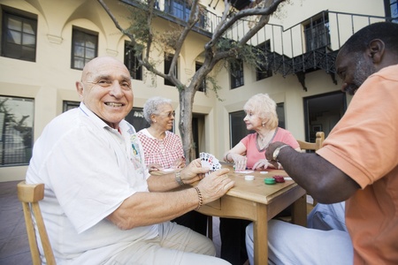 Senior people playing cards smiling