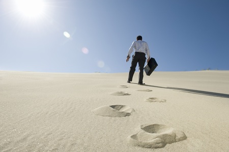 Businessman Walking Uphill With Briefcase in the Desertの写真素材