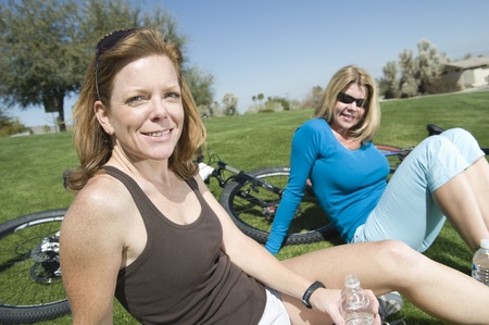 Two friends sit in park with their bikesの写真素材