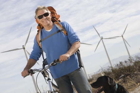 Senior man with bicycle near wind farm