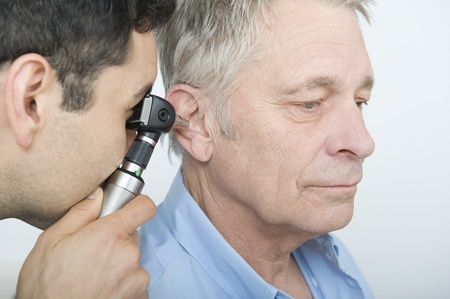 Mid adult doctor checks hearing of senior patient