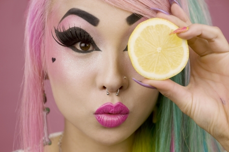Woman holding slice of lime in front of her eyesの写真素材