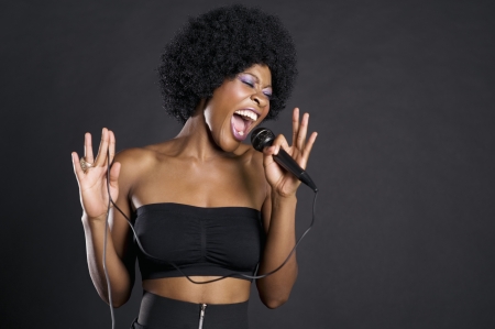 Woman singing on microphone over colored backgroundの写真素材