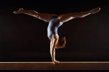 Gymnast (13-15) doing split handstand on balance beam side viewの写真素材