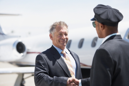 Businessman Beside private jet shaking hands with pilotの写真素材