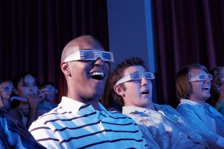 Young men wearing 3-d glasses watching 3-D movie in theatre