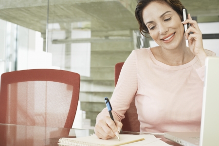 Businesswoman using mobile phone in officeの写真素材