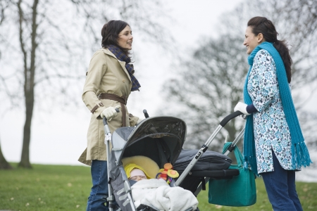 Two mothers in park with babies in strollersの写真素材
